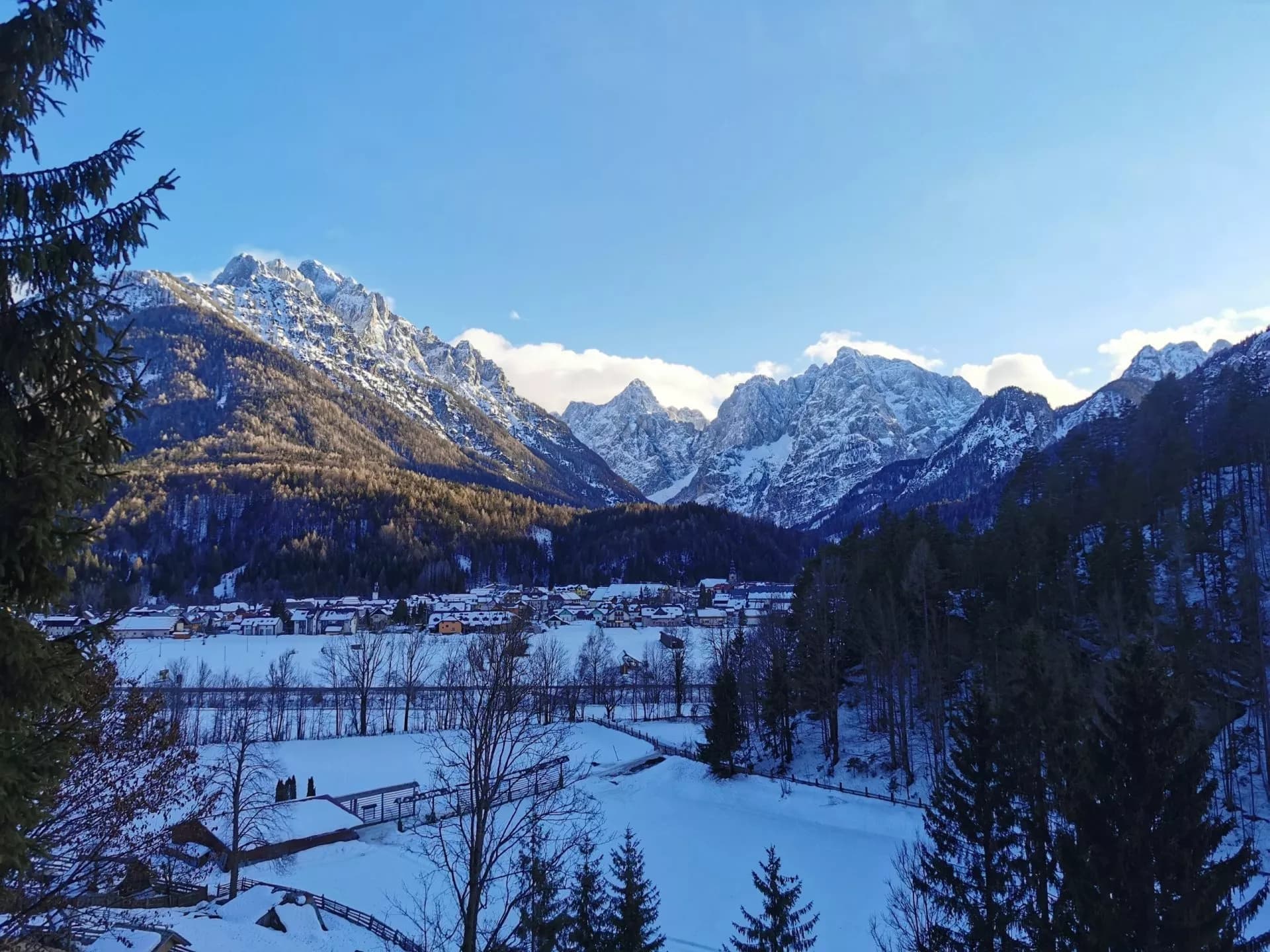 Kranjska Gora panorama in winter with snow-capped mountains above a village.