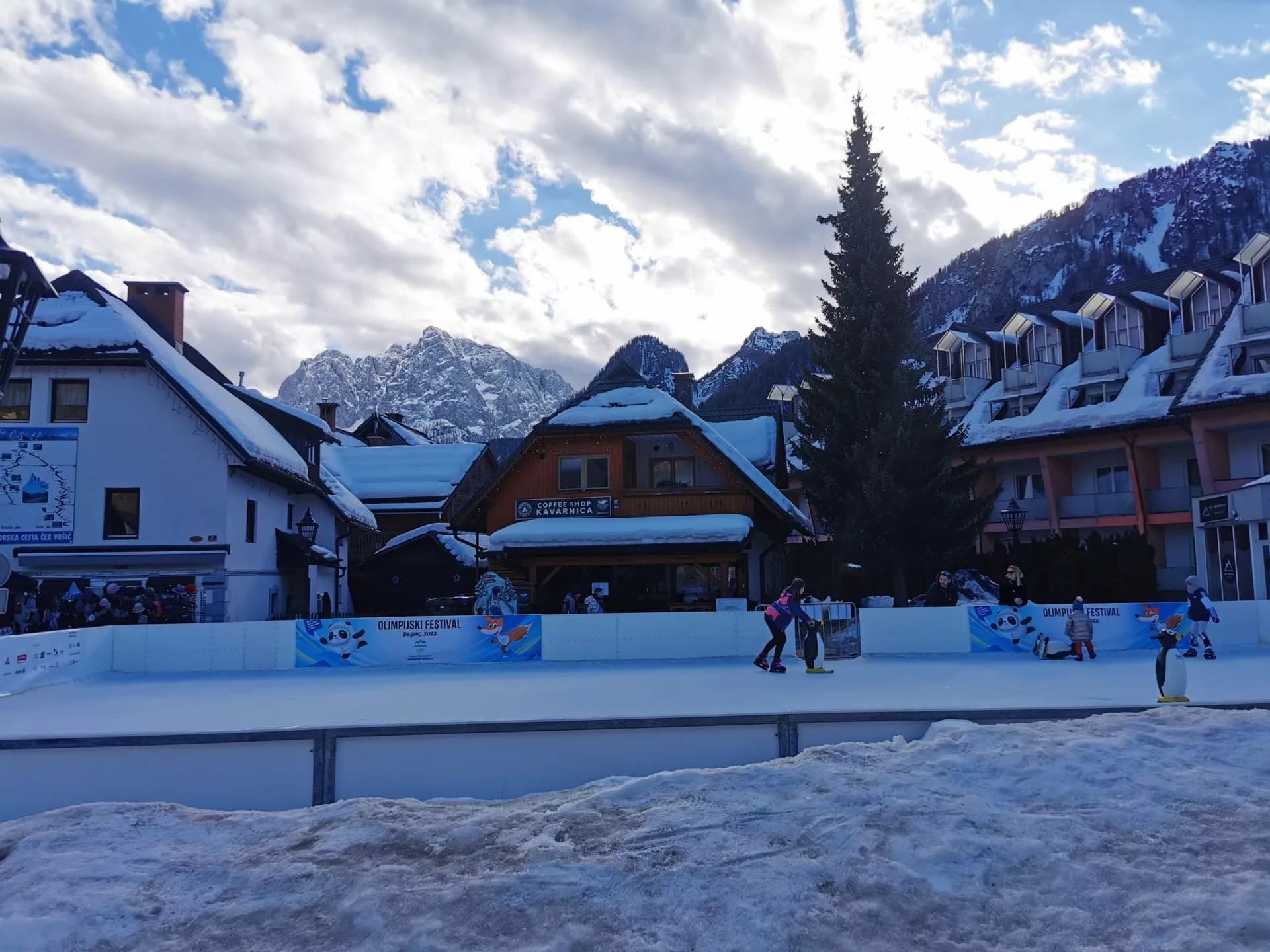 Ice skating rink in Kranjska Gora with snow-covered buildings and mountains.