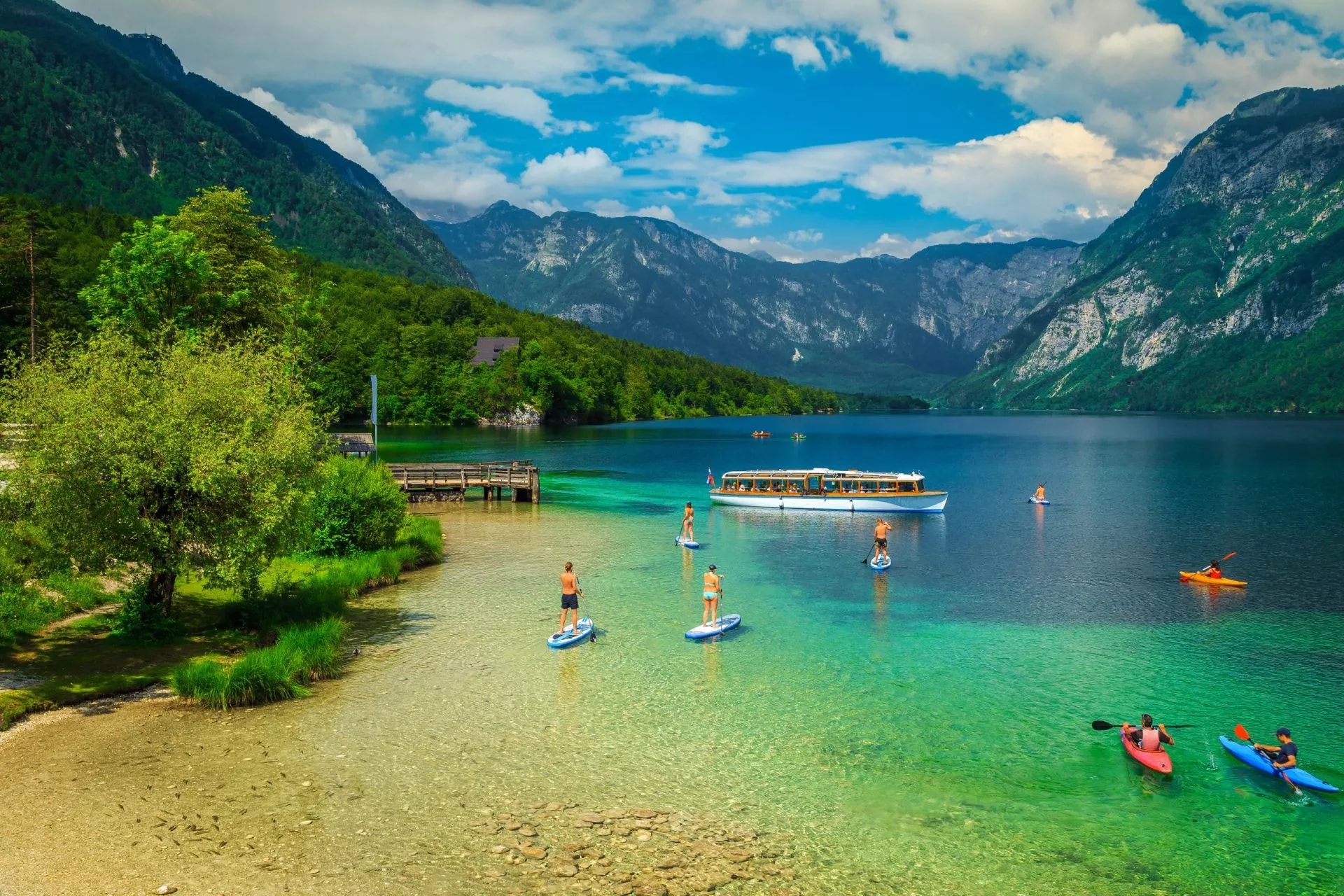 Paddleboarding and kayaking on clear turquoise lake surrounded by steep green mountains