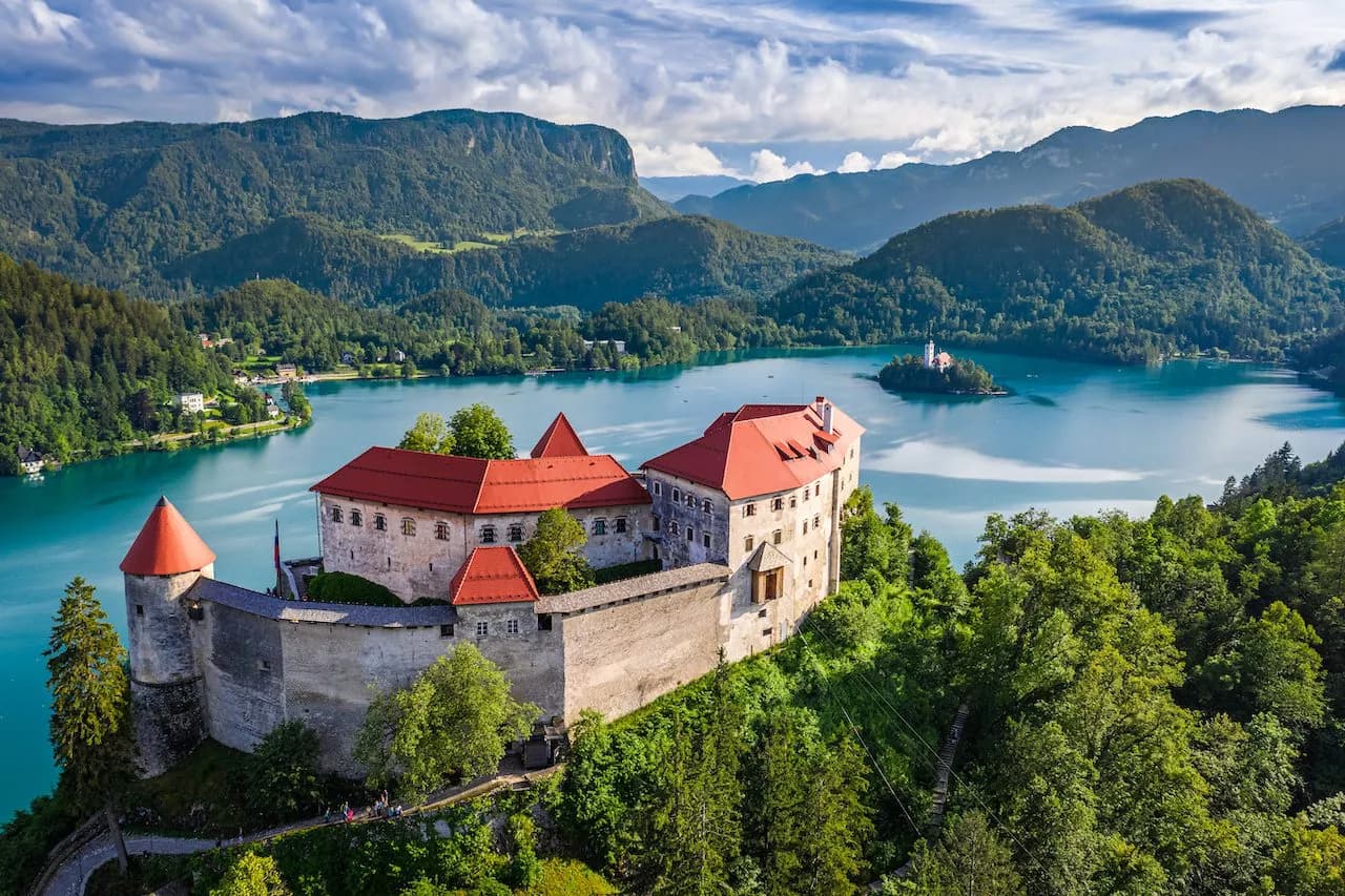 Bled Castle overlooking Lake Bled island church with forested mountains backdrop