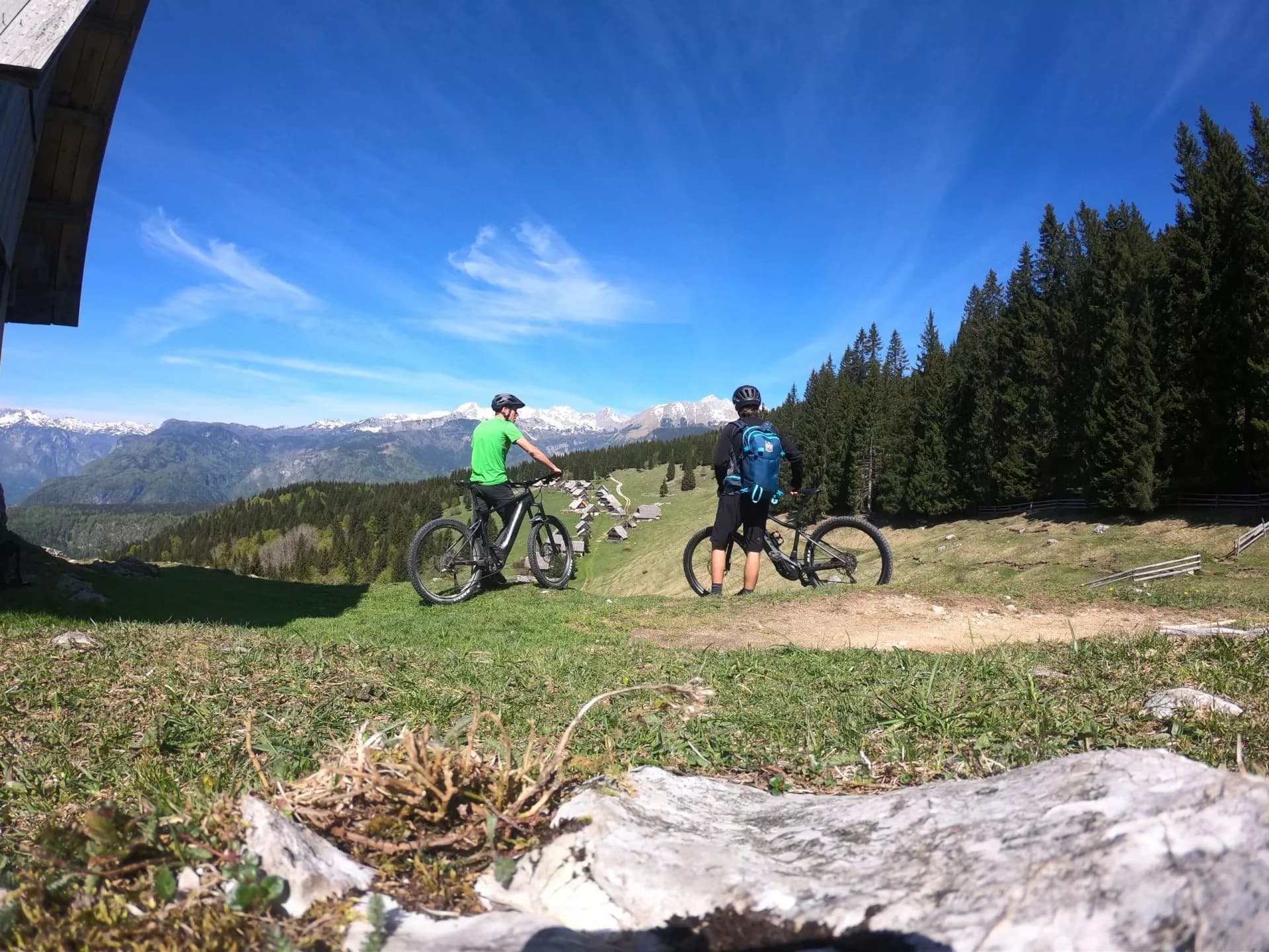 Mountain biking with snow-capped mountains in the background under a bright blue sky.