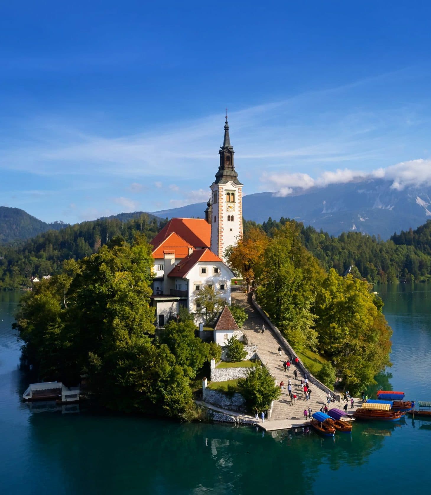 Church on island in Lake Bled with boats docked and mountains in background
